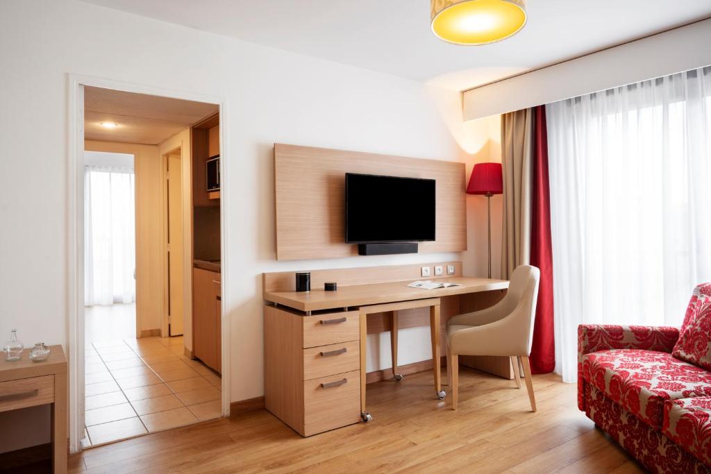 a living room with a desk and a tv in a room at Residhome Paris-Evry in Courcouronnes
