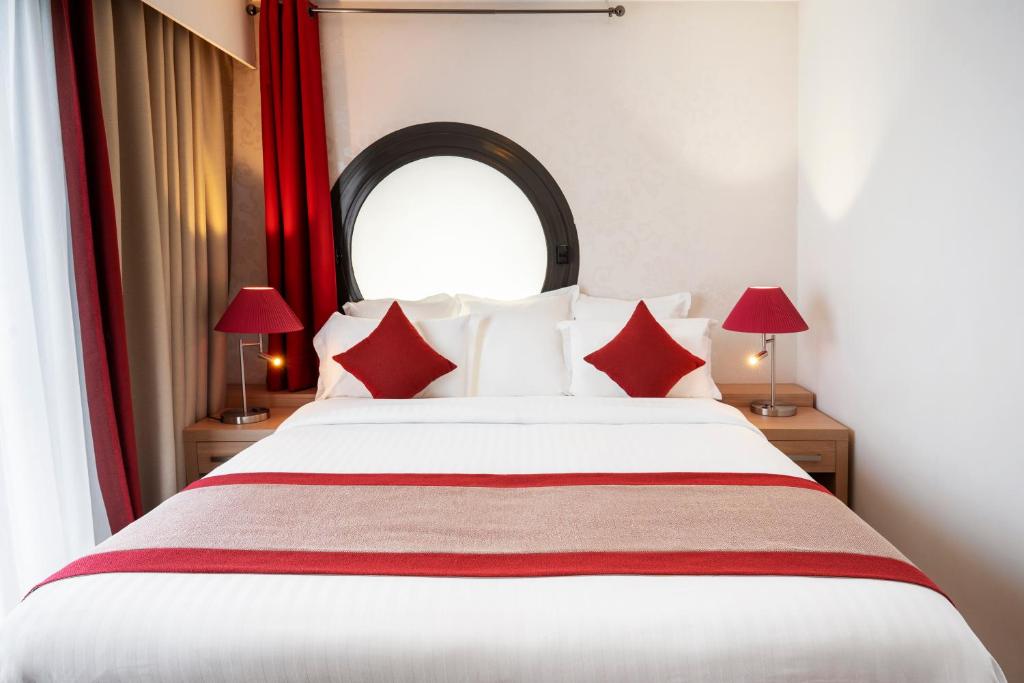 a bedroom with a large white bed with red pillows at Residhome Paris-Evry in Courcouronnes