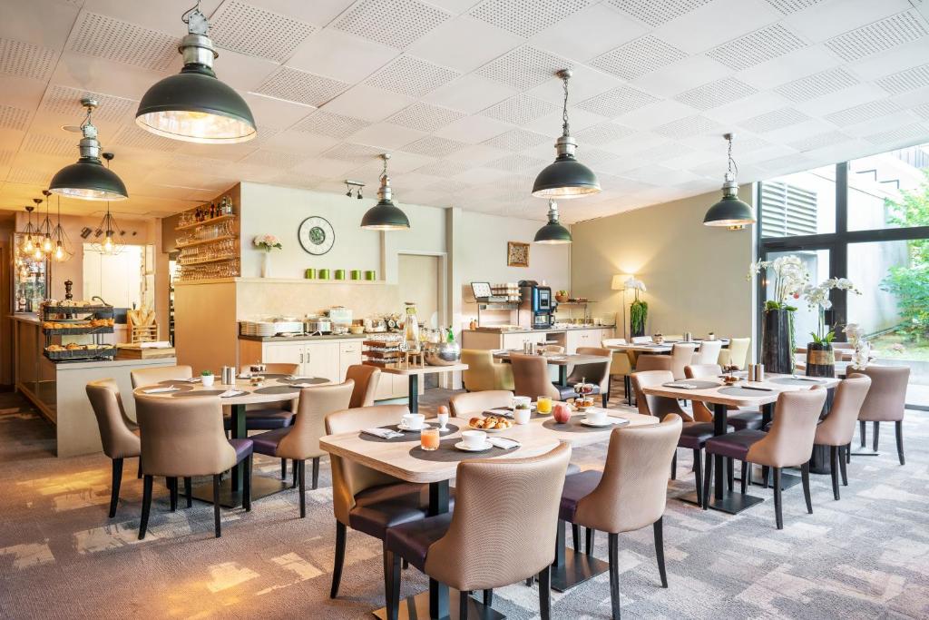 a restaurant with tables and chairs and a kitchen at Residhome Paris-Evry in Courcouronnes