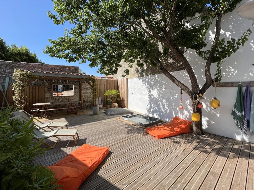 a deck with a tree and orange pillows on it at Maison Rénovée avec Jacuzzi et Cuisine d'Été au Centre du Village - FR-1-434-97 in La Couarde-sur-Mer