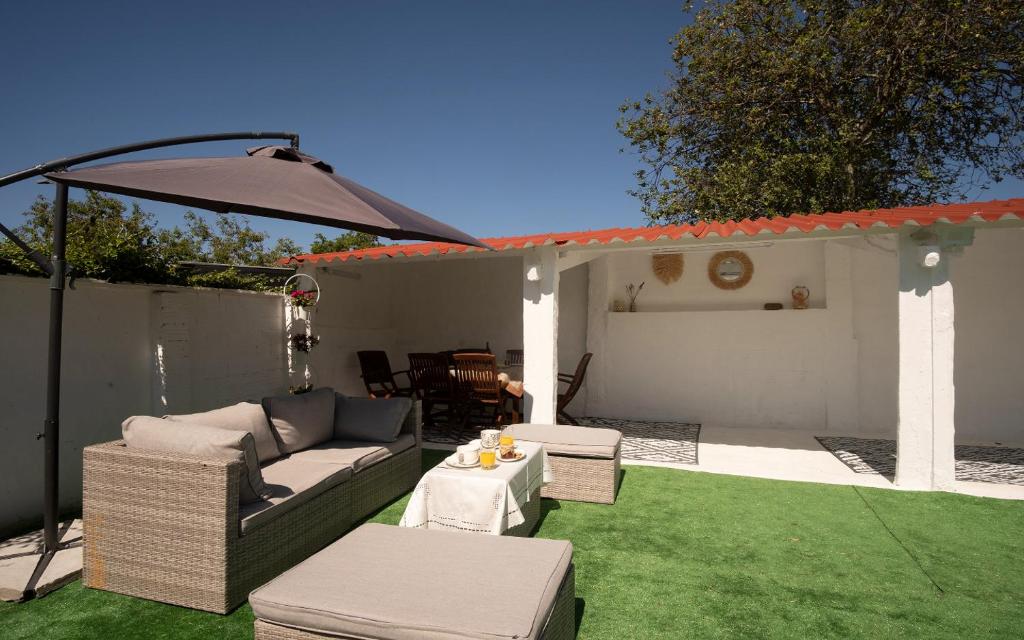 a patio with a couch and an umbrella at Preciosa casa cerca de la playa de Samil in Vigo