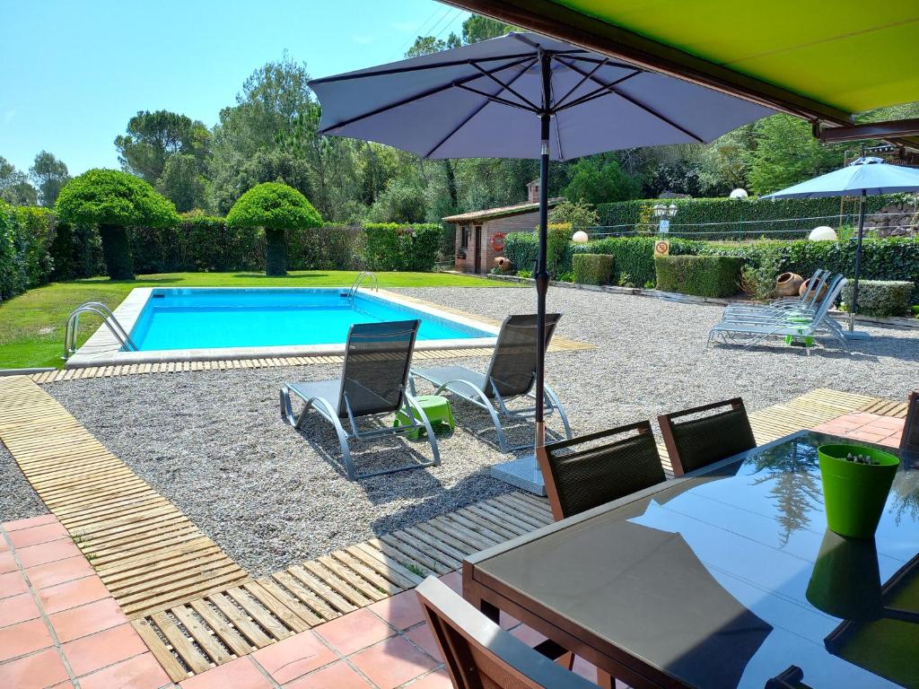 卡佩利亞德斯的住宿－Finca La Pedrera Resort，一个带两把椅子和遮阳伞的游泳池