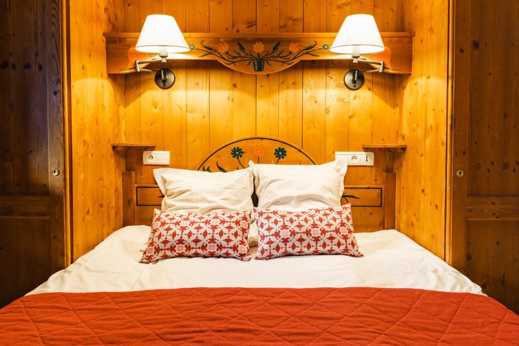 a bedroom with a bed with wooden walls and two pillows at Lagrange Vacances Le Cristal d'Argentière in Chamonix-Mont-Blanc