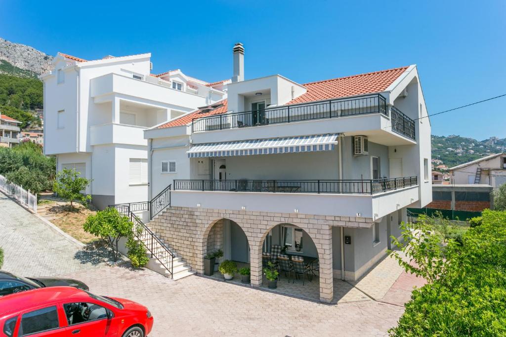 una casa con un coche rojo estacionado frente a ella en Apartments with a parking space Solin, Split - 21445, en Solin