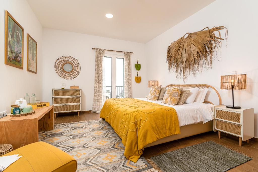 una camera da letto con un grande letto con una coperta gialla di Yeotown Health Retreat ad Arco da Calheta
