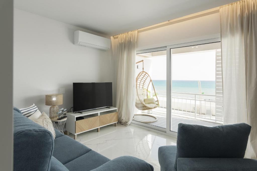 a living room with a couch and a television and a balcony at Miral 5 Sea front by HD Properties in Quarteira