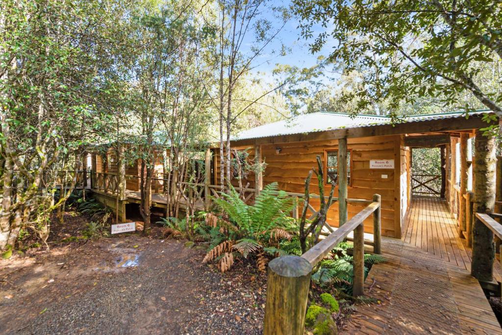 a cabin in the woods with a wooden deck at Cradle forest inn in Moina