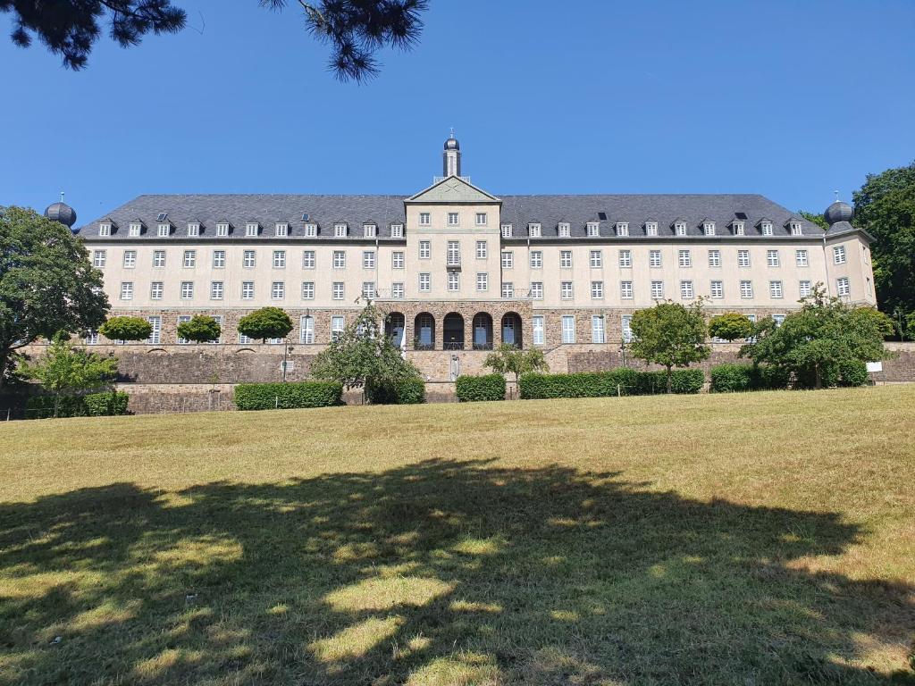 un grand bâtiment blanc avec une grande pelouse devant lui dans l'établissement Kardinal Schulte Haus, à Bergisch Gladbach