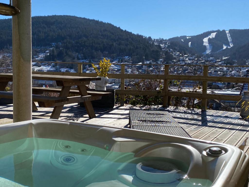 bañera en la parte superior de una terraza con mesa en AU NID COSY D'ISA A GERARDMER VOSGES - Spas privatifs, en Gérardmer