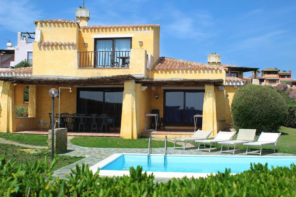 a villa with a swimming pool in front of a house at Villa La Rocca in Stintino