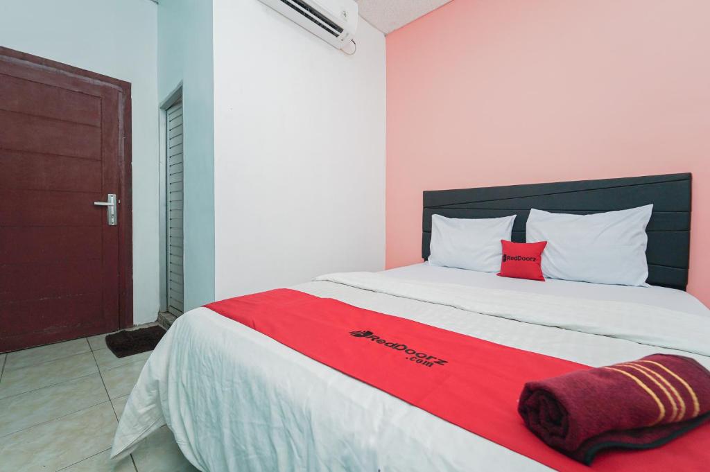 sypialnia z dużym łóżkiem i czerwonym kocem w obiekcie RedDoorz Syariah at MN One Cempaka Putih w Dżakarcie