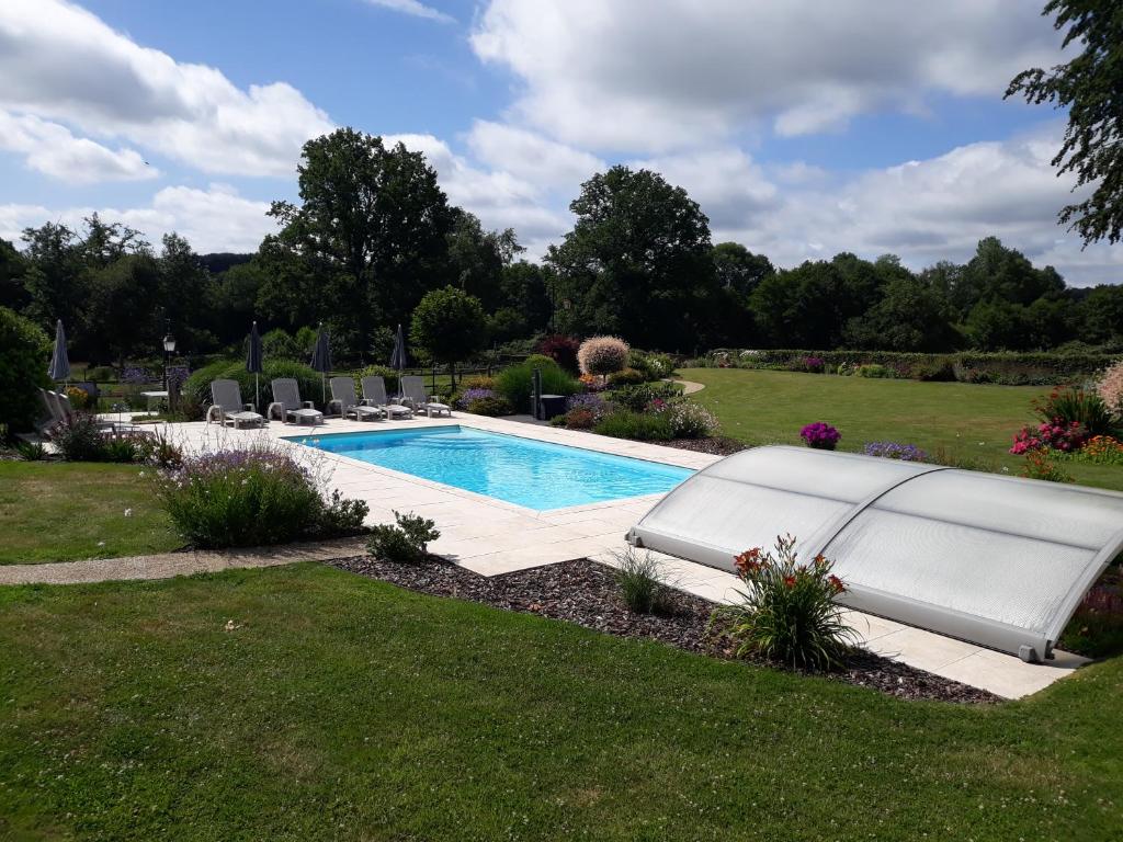 a swimming pool in a yard with chairs and flowers at Gite de la Houssière in Joué-du-Bois