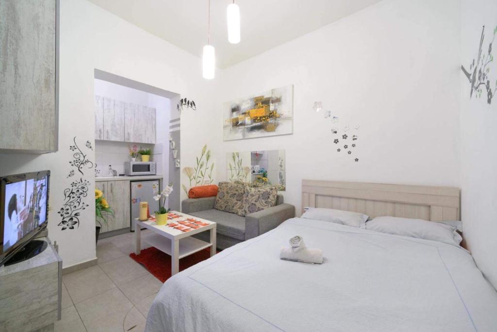 a white bedroom with a bed and a living room at סטודיו חדשה ליד הים רחוב בוגרשוב in Tel Aviv