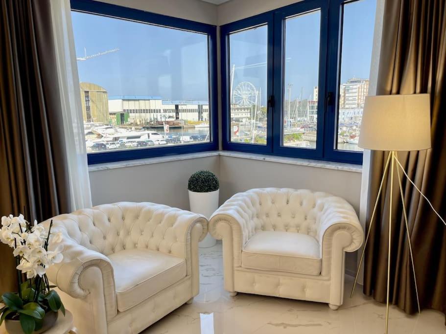 2 sillas blancas en una habitación con ventanas grandes en Darsena Luxury apartments, en Viareggio