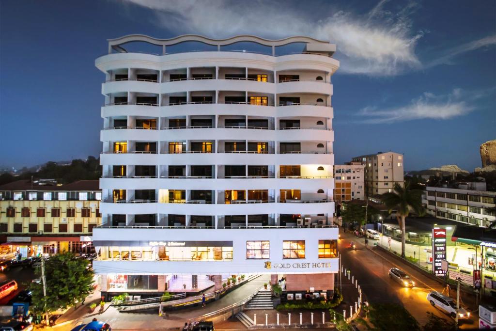 um edifício branco alto com luzes acesas numa cidade em Gold Crest Hotel em Mwanza