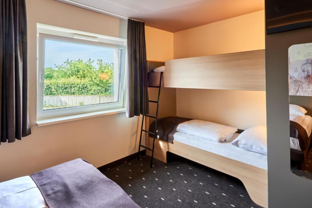 a bedroom with two beds and a window at B&amp;B Hotel Heidelberg in Heidelberg