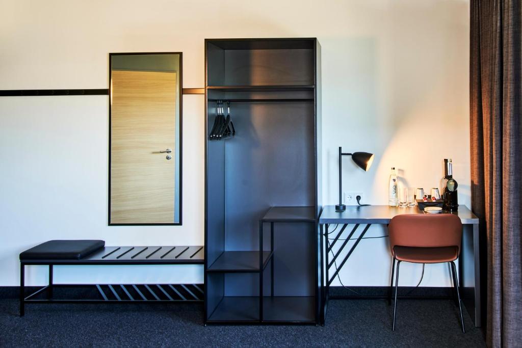 a room with a desk and a chair and a mirror at B&amp;B Hotel Heidelberg in Heidelberg