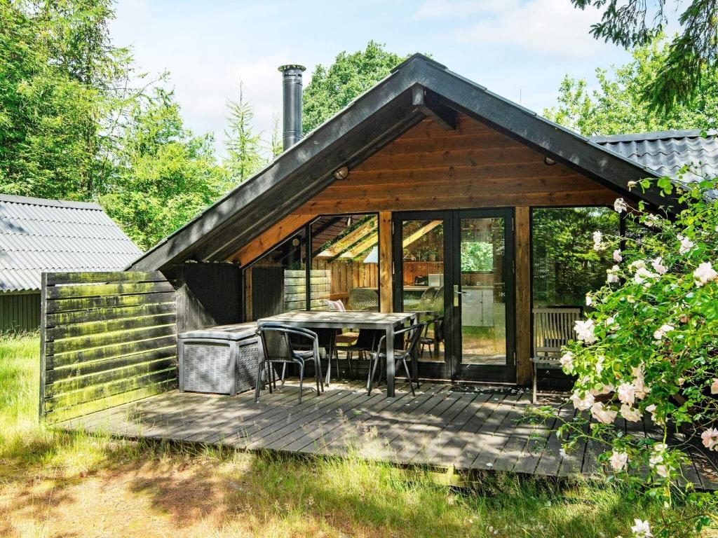 a wooden cabin with a table and chairs on a deck at Holiday home Glesborg LXIII in Glesborg