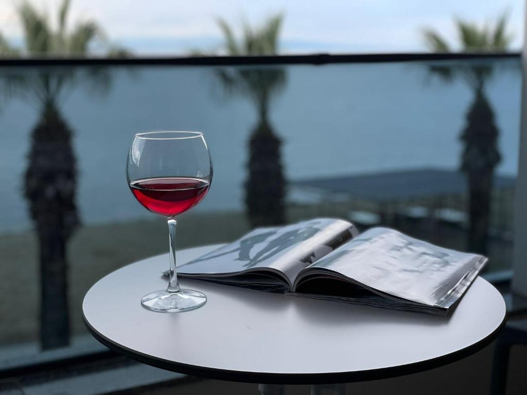 een glas wijn en een boek op een tafel bij Palmon Hotel in Erdek