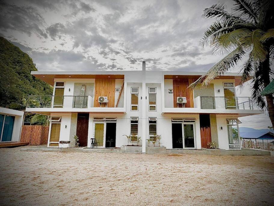 een groot wit huis met een palmboom ervoor bij Ohana beach house - Villa #3 in Cemento