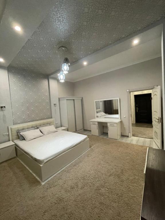 um quarto com uma grande cama branca e uma secretária em Central Apartment em Samarkand