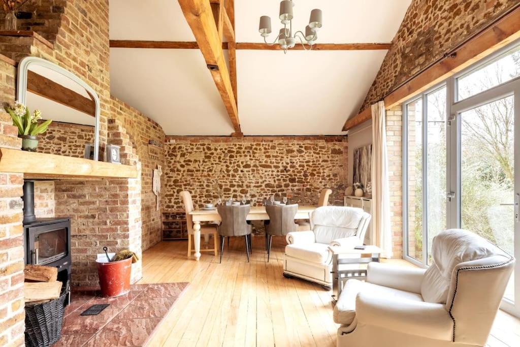 a living room with a brick wall and a table and chairs at The Cart Lodge - relaxing rural spa break in Pentney