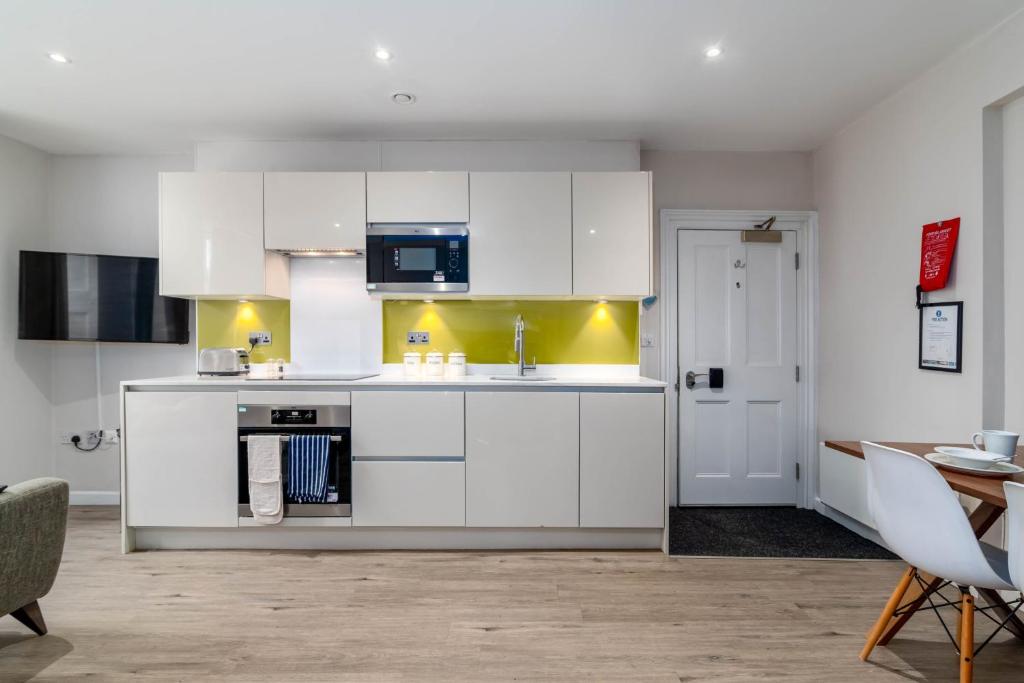 a kitchen with white cabinets and a dining room at Charlotte Rise in Bristol