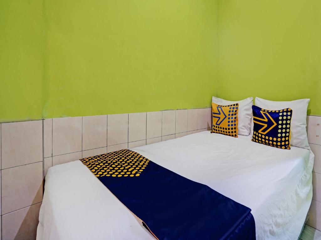 OYO Life 92653 Homestay Griya Nautika Syariah في سورابايا: غرفة نوم بسرير ابيض ومخدات زرقاء وصفراء