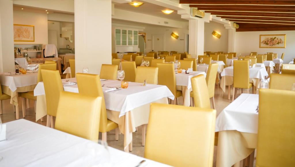 un restaurante con mesas blancas y sillas amarillas en Sirena Suite Deluxe, en Peschici