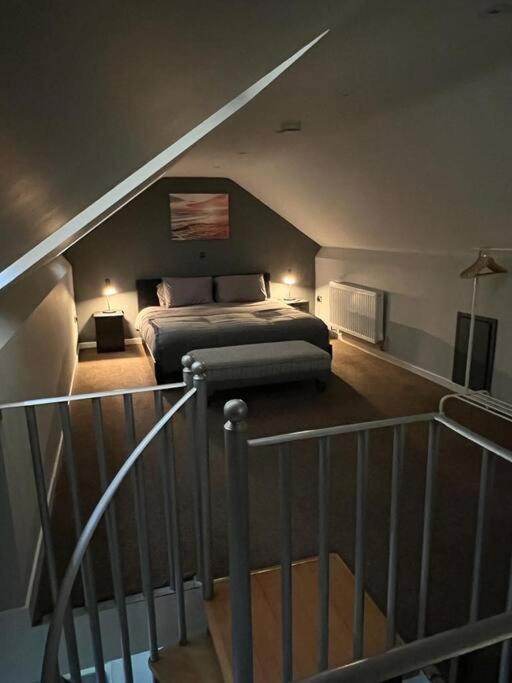 a bedroom with a bed in a attic with a staircase at Superb Three Bed Garnant Duplex! in Garnant