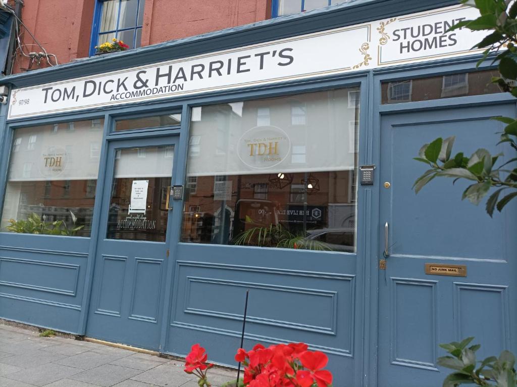 a store front with blue doors and red flowers in front at Tom Dick and Harriet's Accommodation in Dublin