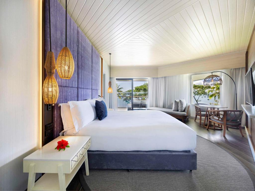 a bedroom with a large bed and a living room at Sofitel Fiji Resort & Spa in Denarau