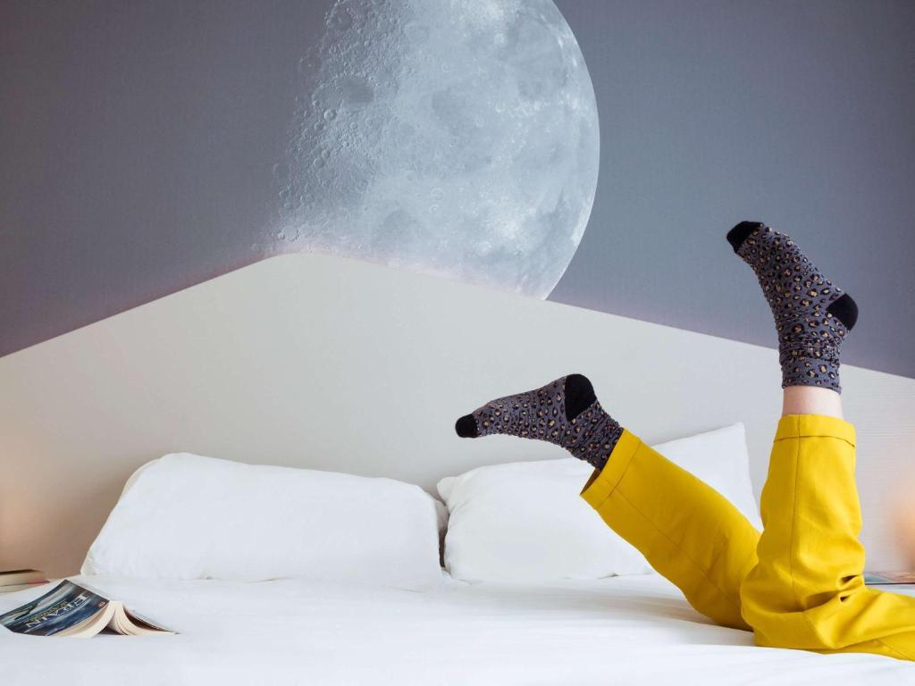 a person with their legs up on a bed with the moon at ibis Styles Paris Charles de Gaulle Airport in Roissy-en-France