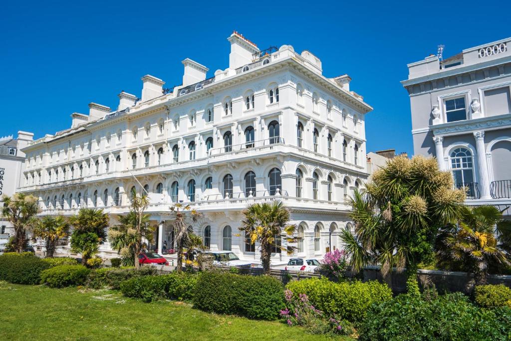 a white building with palm trees in front of it at 1 Elliot Terrace in Plymouth