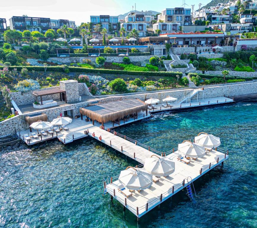 un muelle con sillas y sombrillas en el agua en Allium Bodrum Resort & Spa, en Yalıkavak