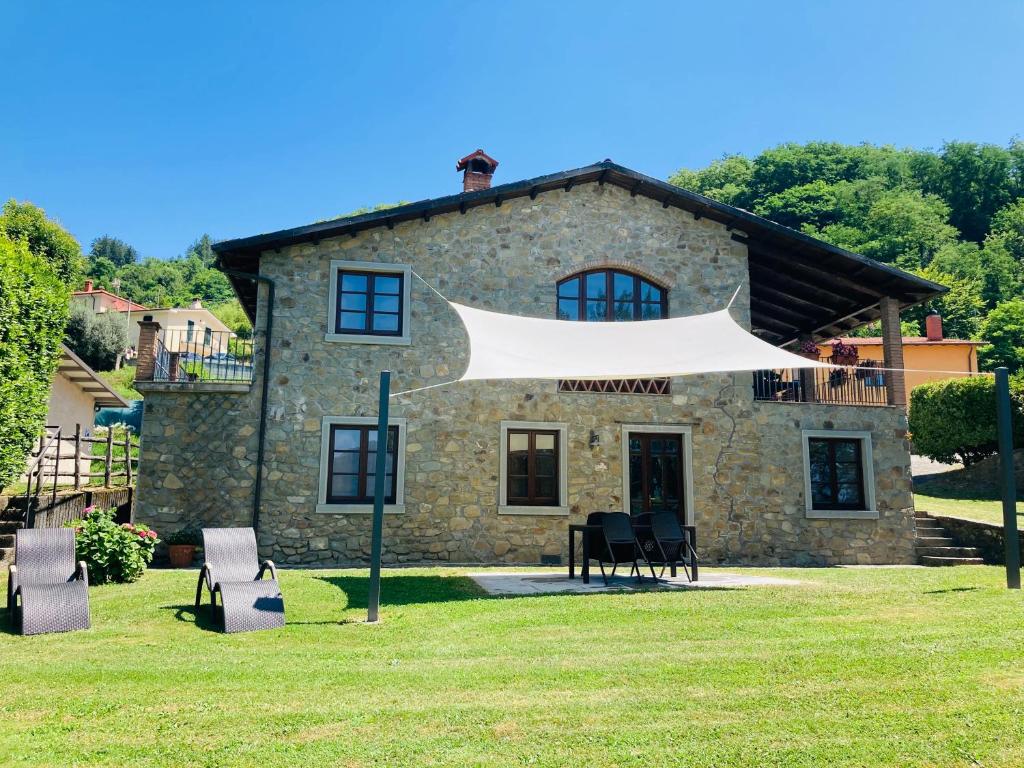 a stone house with a white tent in front of it at Agriturismo Poderino in Castiglione di Garfagnana