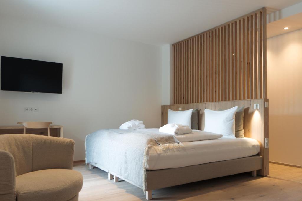 Anett hotel في فيبيتينو: غرفة نوم بسرير وكرسي وتلفزيون