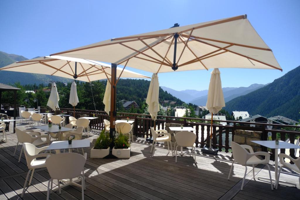 a restaurant with tables and umbrellas on a deck at Hôtel Restaurant Le Chalet d'Auron et Spa Inclus in Auron