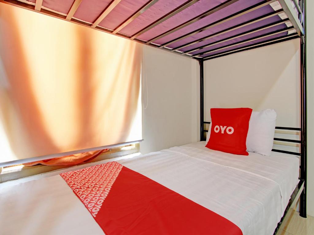Una cama con una almohada roja encima. en OYO 92617 Omahku Homestay Hostel, en Yogyakarta