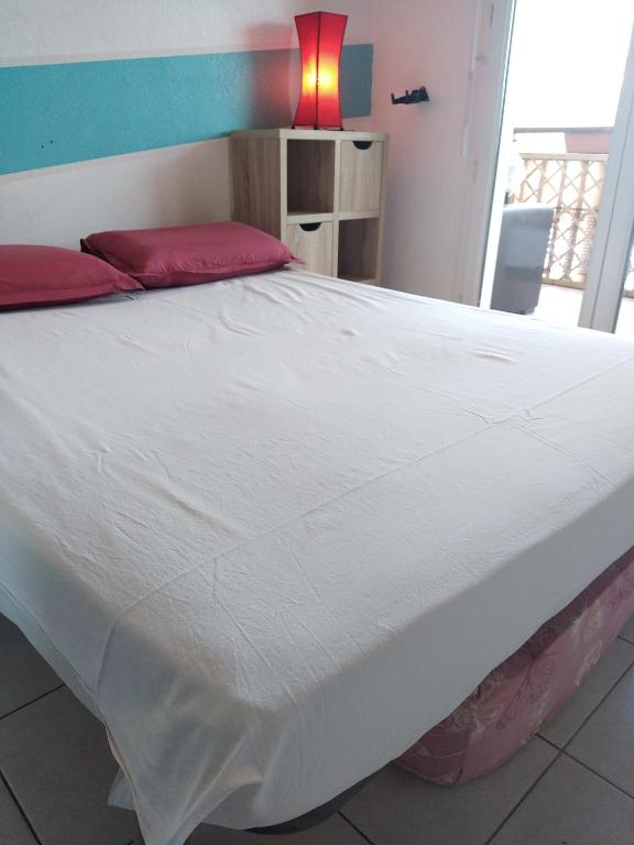 a large bed with white sheets and red pillows at Rêve d une nuit d été in Aubagne