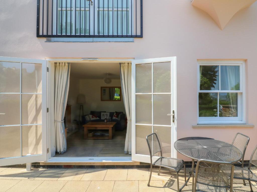 a patio with a table and chairs in front of a house at 5 Combehaven in Salcombe