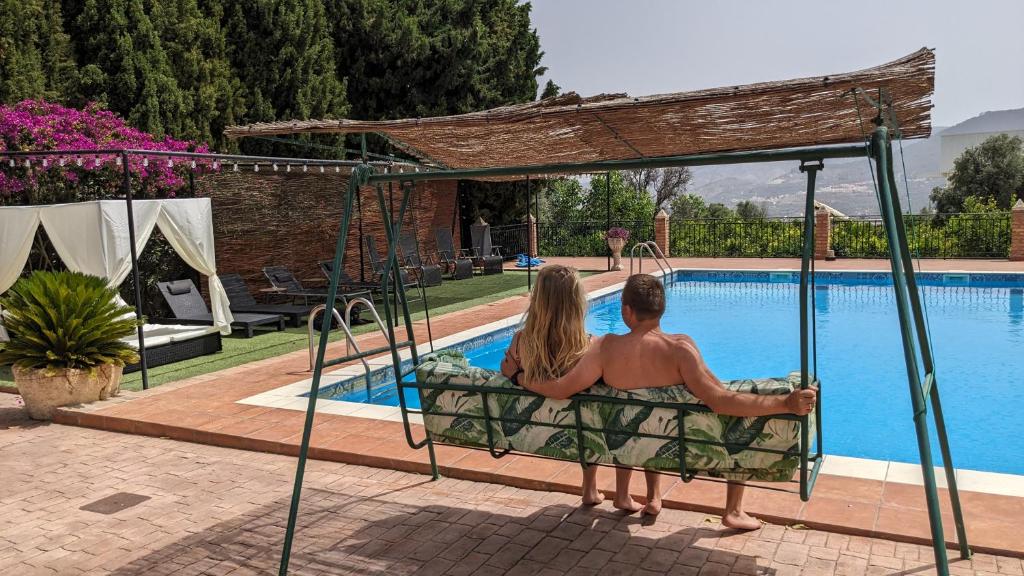 La Cañota Suite King Rooms Adults Only في Talara: رجل وامرأة يجلسون على مرجيحة بجوار حمام السباحة