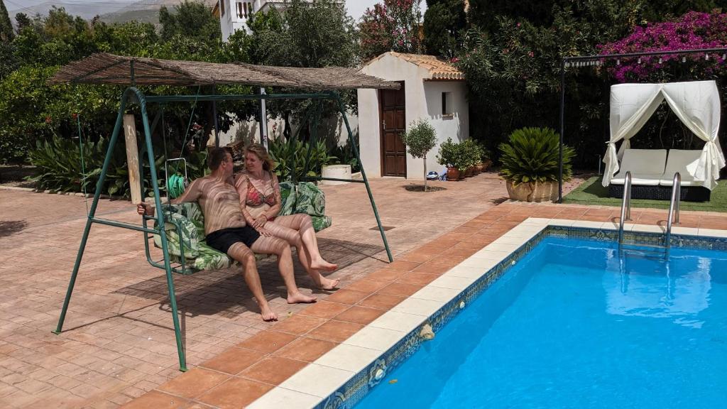 Talara的住宿－La Cañota 2-Floors King Rooms Adults Only，两个女人坐在游泳池旁的椅子上