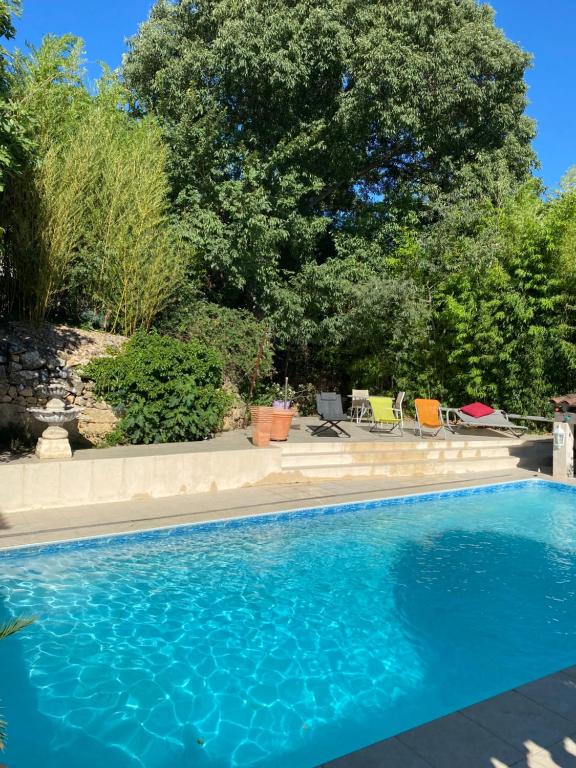 une piscine avec des chaises et des arbres en arrière-plan dans l'établissement L’appartement du Micocoulier, à Salon-de-Provence