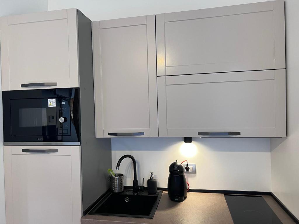 a white kitchen with a sink and a microwave at La Vita in Ravascletto