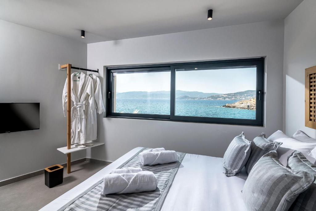 Schlafzimmer mit einem großen Fenster mit Blick auf das Wasser in der Unterkunft Sea Front Salty Sea Suites Estate in Agios Nikolaos