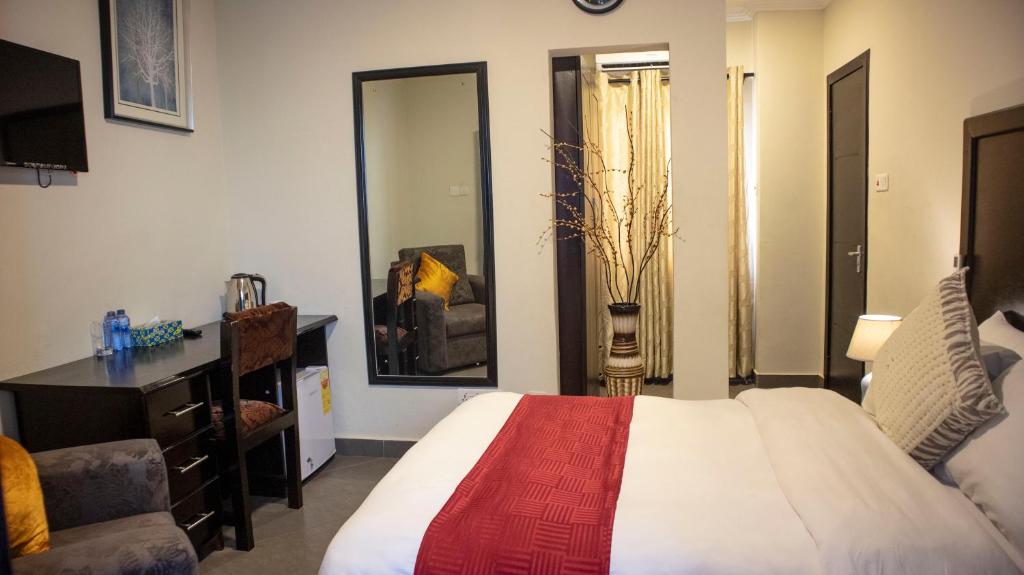 ein Schlafzimmer mit einem Bett, einem Stuhl und einem Spiegel in der Unterkunft SSNIT GUEST HOUSE in Nima