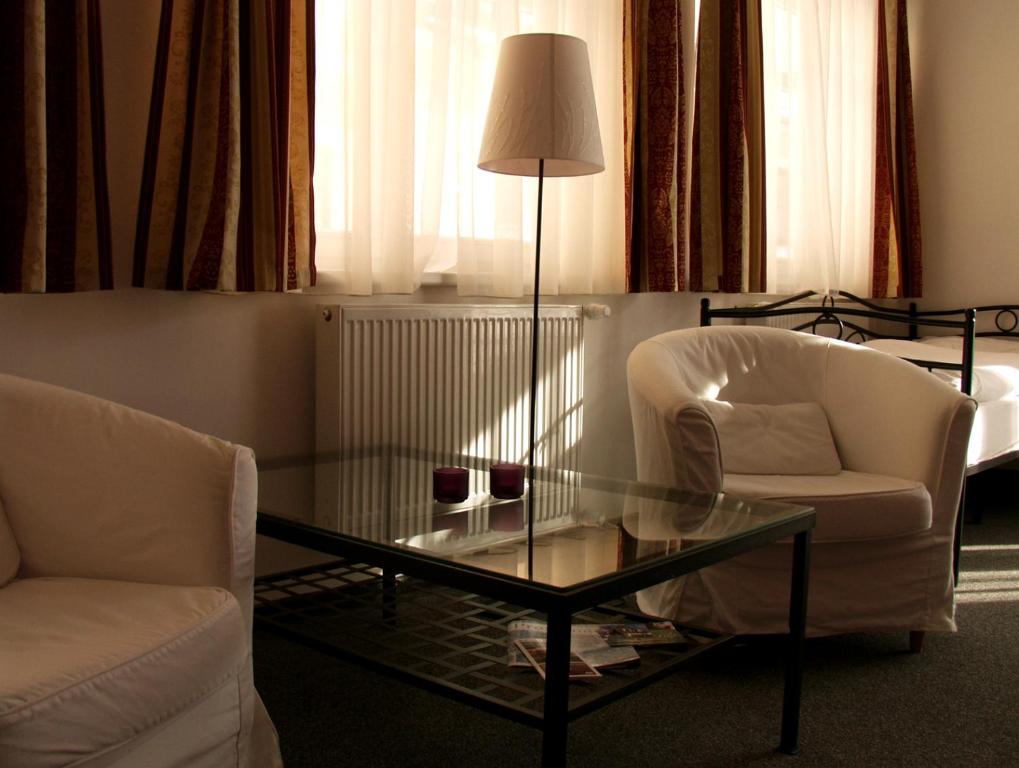 a living room with a glass table and two chairs at Apartma La Provence in Mariánské Lázně