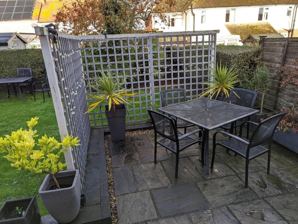 d'une terrasse avec une table, des chaises et une clôture. dans l'établissement Cadborough Cliff Apartment, à Rye