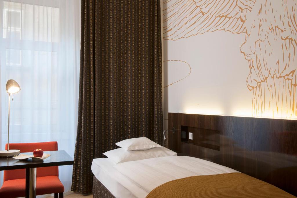 ウィーンにあるアルマ ブティック-ホテルのベッド、テーブル、窓が備わる客室です。